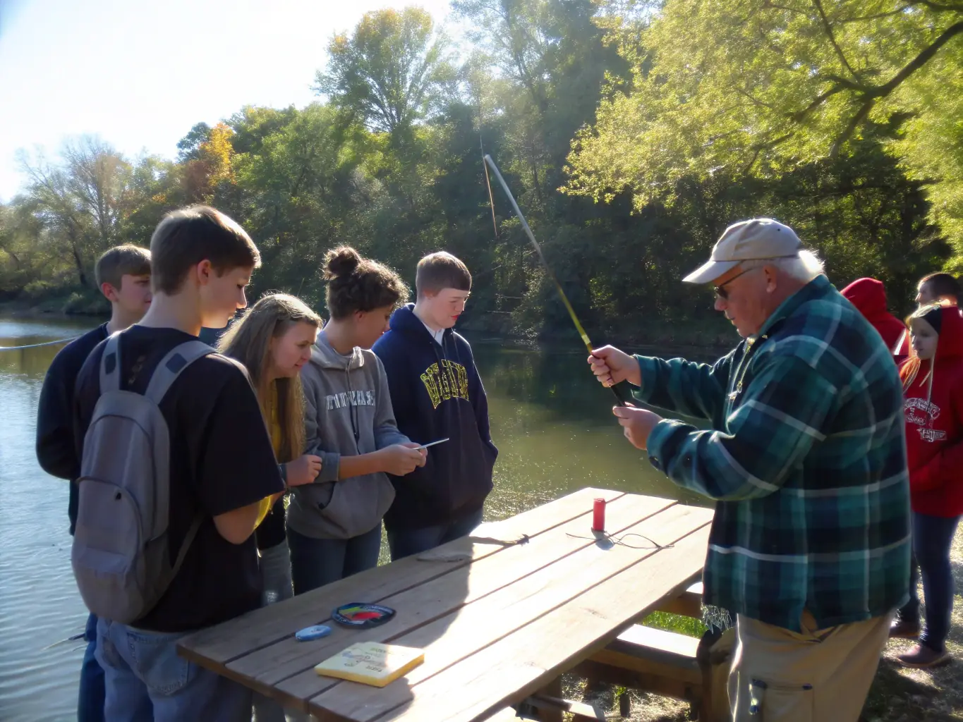 A group of people participating in a fishing workshop by the pond, learning about responsible fishing techniques from an instructor.