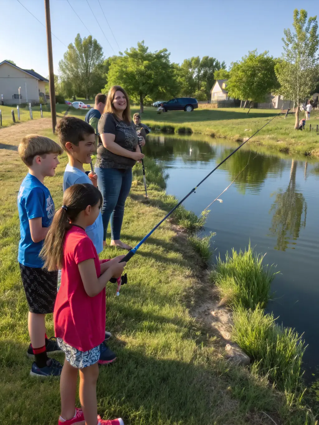 A diverse group of community members gathered at the AURIGIE PECHE pond for a community fishing day, enjoying a day of fishing, food, and camaraderie.